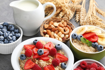 Oatmeal in plate with berries, nuts and jar of milk on wooden table