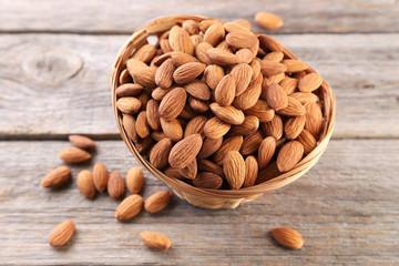 Almonds in basket on grey wooden table