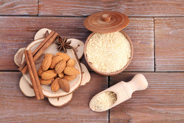 Almonds in bowl and scoop with cinnamon on wooden table