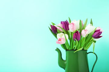 Bouquet of tulips in jug on green background
