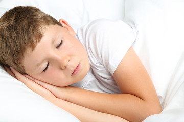 Obraz na płótnie Canvas Young boy sleeping in white bed
