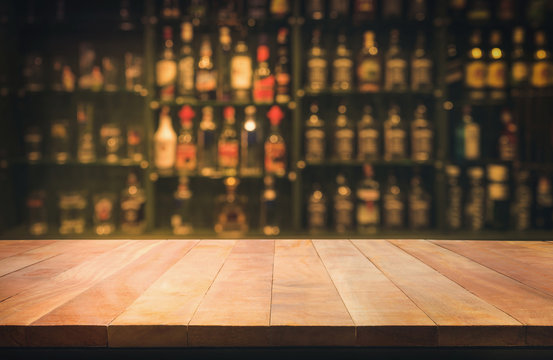 Naklejki Empty the top of wooden table with blurred counter bar and bottles Background