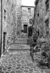  Beautiful view of idyllic alley way in famous Civita di Bagnoregio near Tiber river valley, Lazio, Italy. Black and white