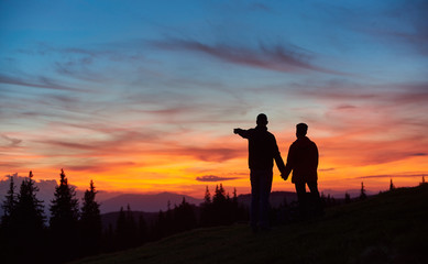 Loving couple enjoying sunset while hiking in the mountains together. Man pointing to the sky copyspace love people affection romance nature landscape travelling