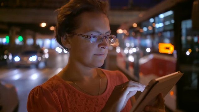 Woman using digital tablet computer in city at night