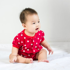 Portrait of adorable baby sitting on a white floor and smiling with copyspace