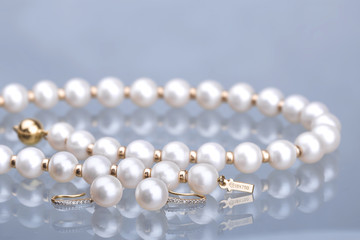 Close up shot of a Beautiful Beaded Pearl and gold necklace on blue background 