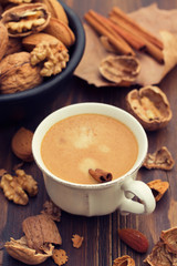 a cup of coffee and nuts on wooden background