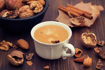 a cup of coffee and nuts on wooden background