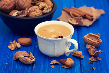 a cup of coffee and nuts on wooden background