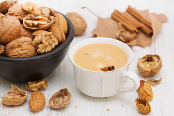 a cup of coffee and nuts on wooden background