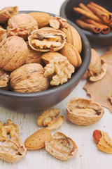 walnuts and almond on black bowl on wooden background