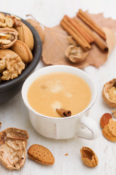 a cup of coffee and nuts on wooden background