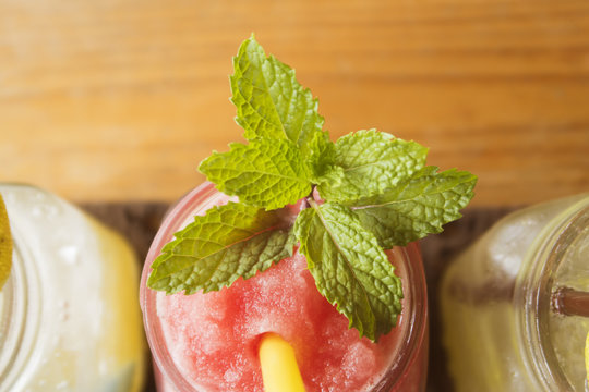 watermelon juice and lemon juices in glass with mint leaves and yellow straw on wooden table. healthy smoothie drink.