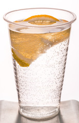 Plastic disposable glass with mineral water and a slice of lemon