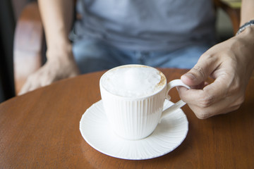 Man holding a white cup of hot coffee.