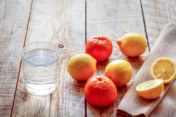 composition of lemons, oranges and glass with water  wooden tabl