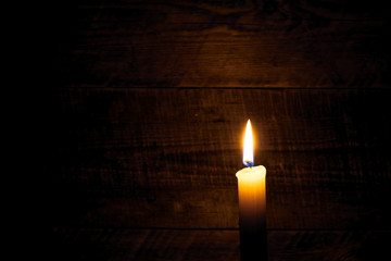 one wax candle on old wooden background