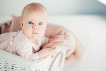 A cute little baby is looking into the camera. baby could be a boy or girl and has blue eyes