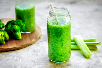 Green vegetable smoothie in glass at gray background