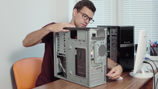 Computer service worker repair a broken computer in the office using a screwdriver and upgrading computer hardware. Support team. Computer maintenance. Shot in 4k
