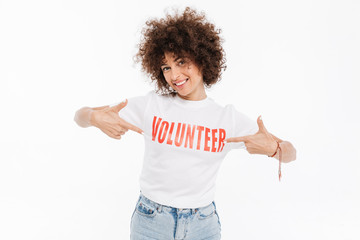 Smiling casual woman pointing two fingers at volunteer shirt