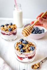 Cooking breakfast with granola and berries on white kitchen back