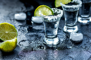Fototapeta na wymiar Alcohol shots with lime and salt on black background