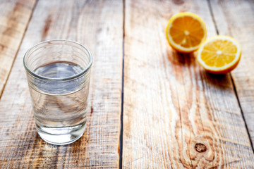 glass of fresh water with halved lemon on wooden table