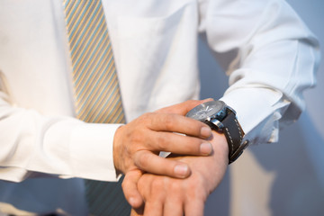 Fototapeta na wymiar The groom wears and adjust a wristwatch. The groom looks at his watch. Wedding detail preparation.