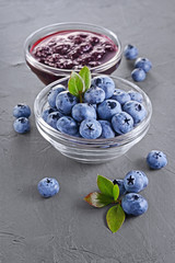 Close up view jam in glass bowl with fresh ripe blueberry and leaves