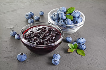 Close up view jam in glass bowl with fresh ripe blueberry and leaves
