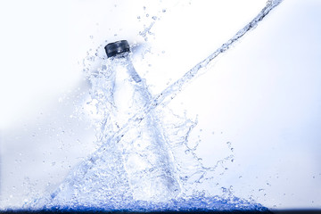 Naklejka na ściany i meble Water splash drop to bottle refreshing product with splashing aqua elements on white background . Close up of splash of water forming explode shape