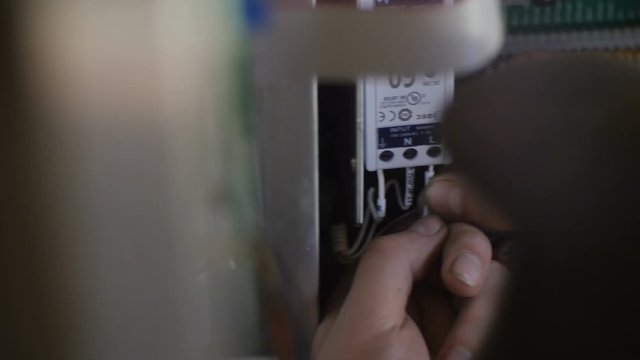 Motion Past Skilled Worker Fixing Wires at Switchboard