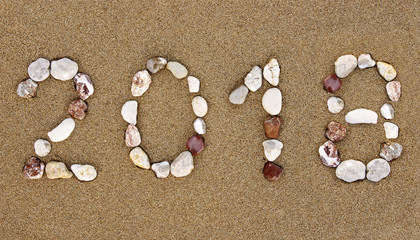 Fototapeta na wymiar Pebble New Year 2018 number on wet sandy beach. New Year 2018 concept.