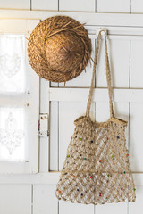 Interior of light modern wooden house inside, vintage window with shutters and decorative curtains. Straw hat and handmade wicker bag. Rustic and village style © Oleg Breslavtsev