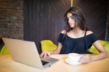 Fototapeta premium Beautiful brunette using laptop in cafe