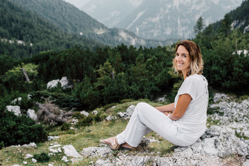Naklejka na ściany i meble Woman sitting on a and enjoying beautiful landscape/ mountain and clouds 