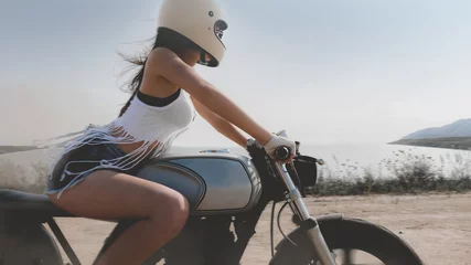 Cercles muraux Moto Femme sexy dans un casque de protection roulant vite sur sa moto de course de café sur mesure dans le désert