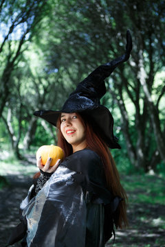 Portrait of cheerful witch in hat with pumpkin