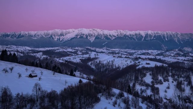 Winter sunrise with amazing light over mountains and village. 4k timelapse. 	Isolated houses in foreground and Piatra Craiului panorama in background at sunrise. Piatra craiului Mountains are shaddowe
