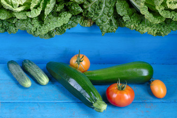 Vegetables. Tomato, cucumber, zucchini and cabbage. Organic food on rustic blue wooden background.