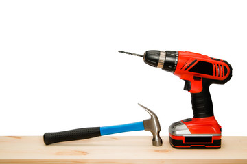 Cordless, driller and hammer on wooden board isolated on white background