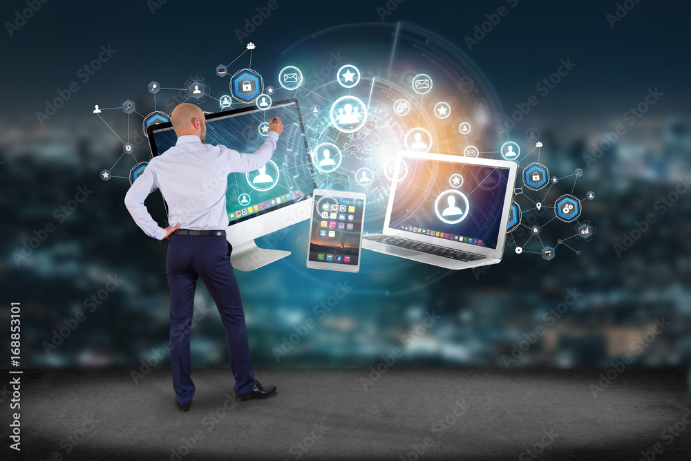 Poster businessman in front of a wall with computer and devices displayed on a futuristic interface with bu
