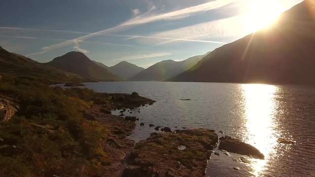 Lake district low aerial shots over rocks and water at sunrise.