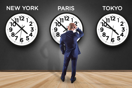 Businessman in front of a wallwith clocks of different country - Jetlag concept