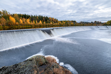 Landscape with autumn forest and dam on the river, Finland