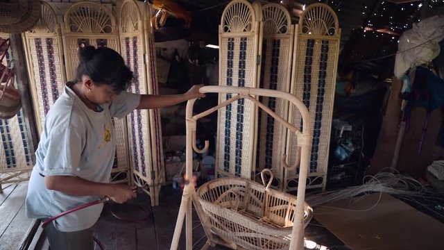 Indonesian woman treating rattan stand with fire in wicker furniture workshop. Shot with Sony a7s and Atomos Ninja Flame