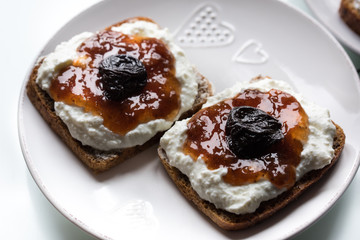 Breakfast with dark bread with white cheese and jam and coffee.  