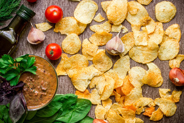 Potato chips with dipping sauce on a wooden table. Unhealthy food on a wooden background.